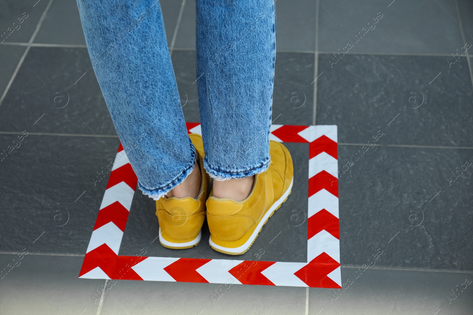 Photo of Woman standing on taped floor marking for social distance, closeup. Coronavirus pandemic