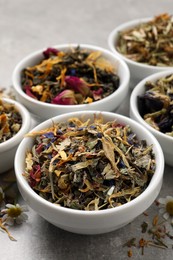 Photo of Different dry aromatic teas on light grey table