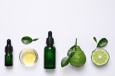 Photo of Bergamot essential oil and fresh fruits on white background, flat lay. Space for text