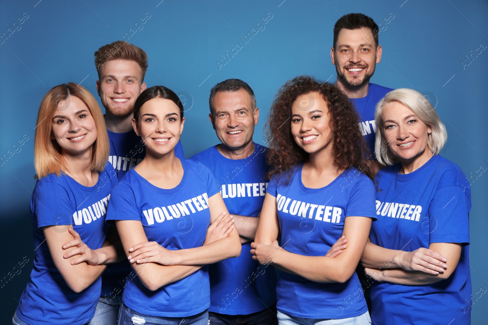 Photo of Team of volunteers in uniform on blue background