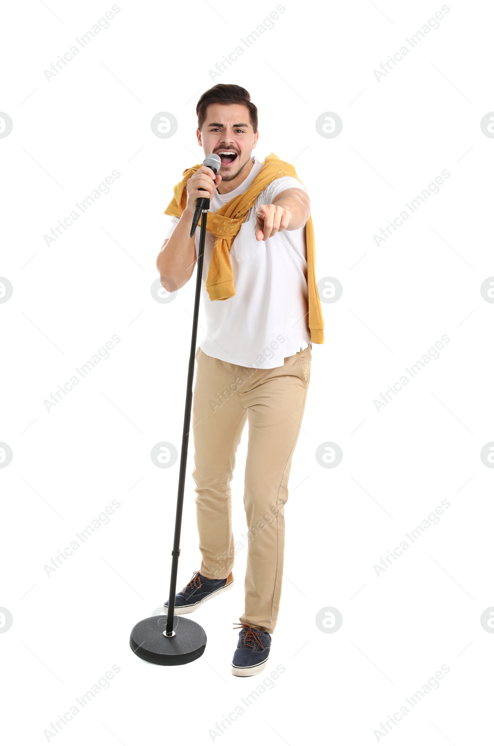 Photo of Young handsome man in casual clothes singing with microphone on white background