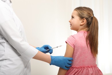 Photo of Doctor giving injection to little girl in hospital. Immunization concept
