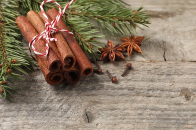 Photo of Different spices and fir branches on wooden table, closeup. Space for text