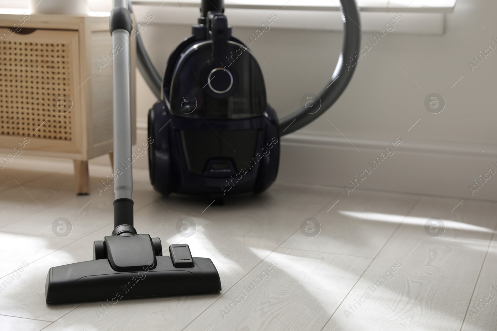 Photo of Modern vacuum cleaner on floor indoors, space for text