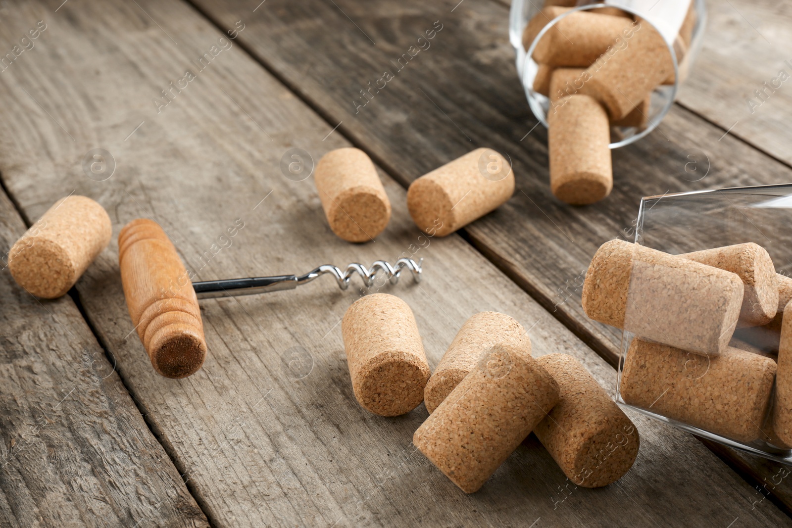 Photo of Glasses with wine corks and corkscrew on wooden table