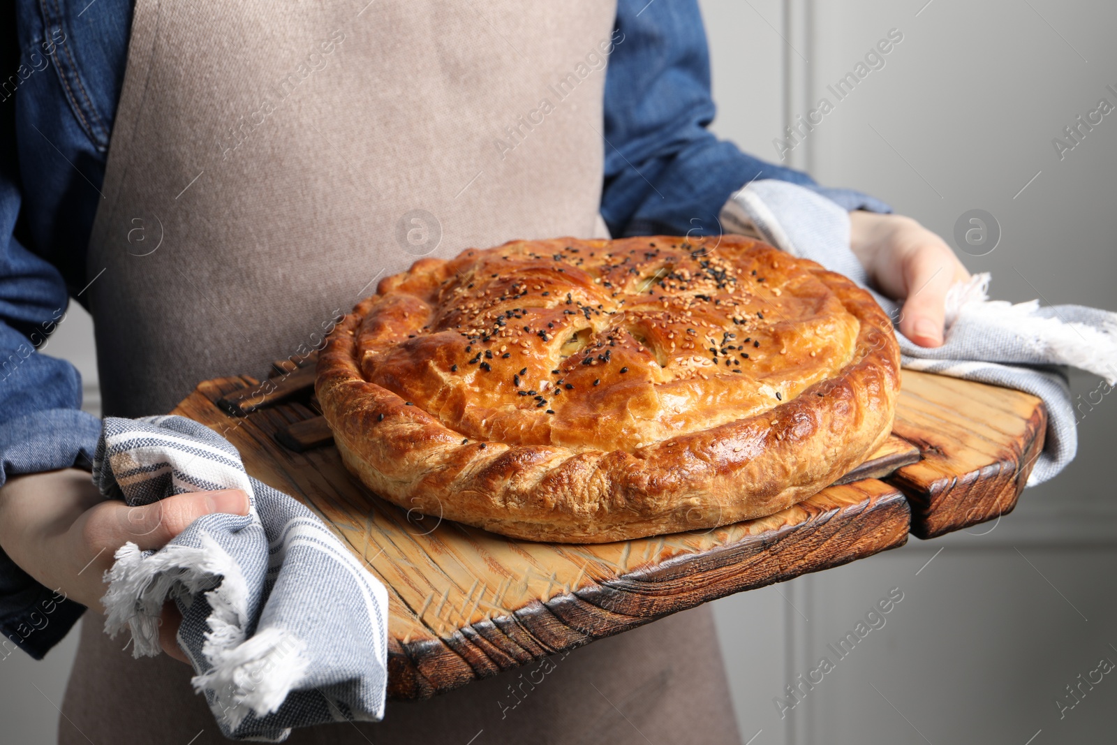 Photo of Woman holding tasty homemade pie indoors, closeup