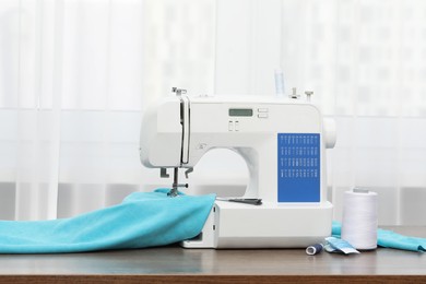 Photo of Sewing machine with fabric and craft accessories on wooden table indoors