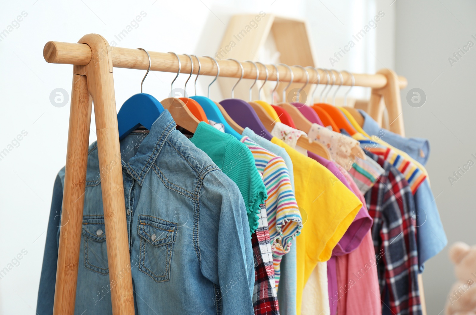 Photo of Different child's clothes hanging on rack indoors, closeup