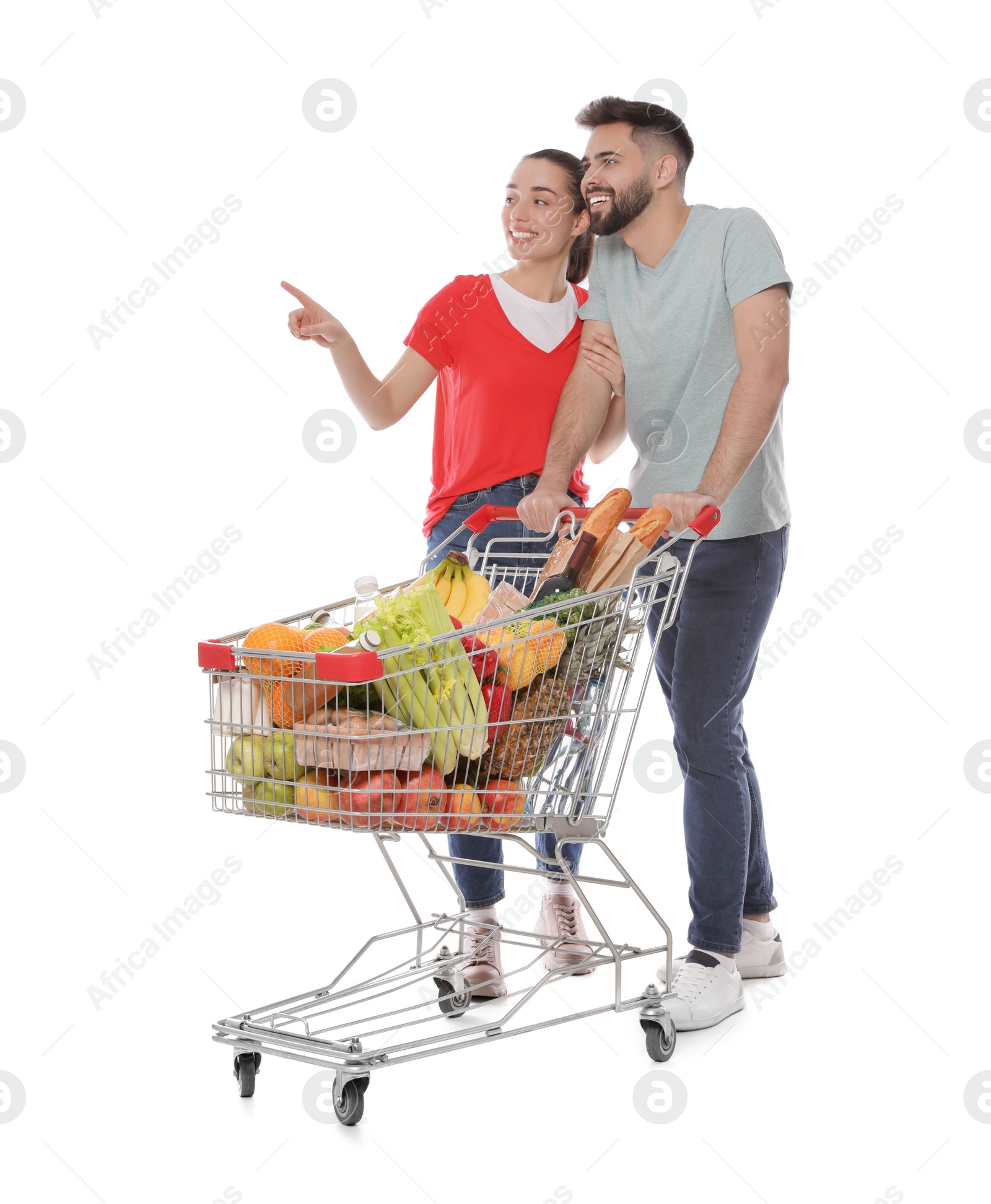 Photo of Happy couple with shopping cart full of groceries on white background