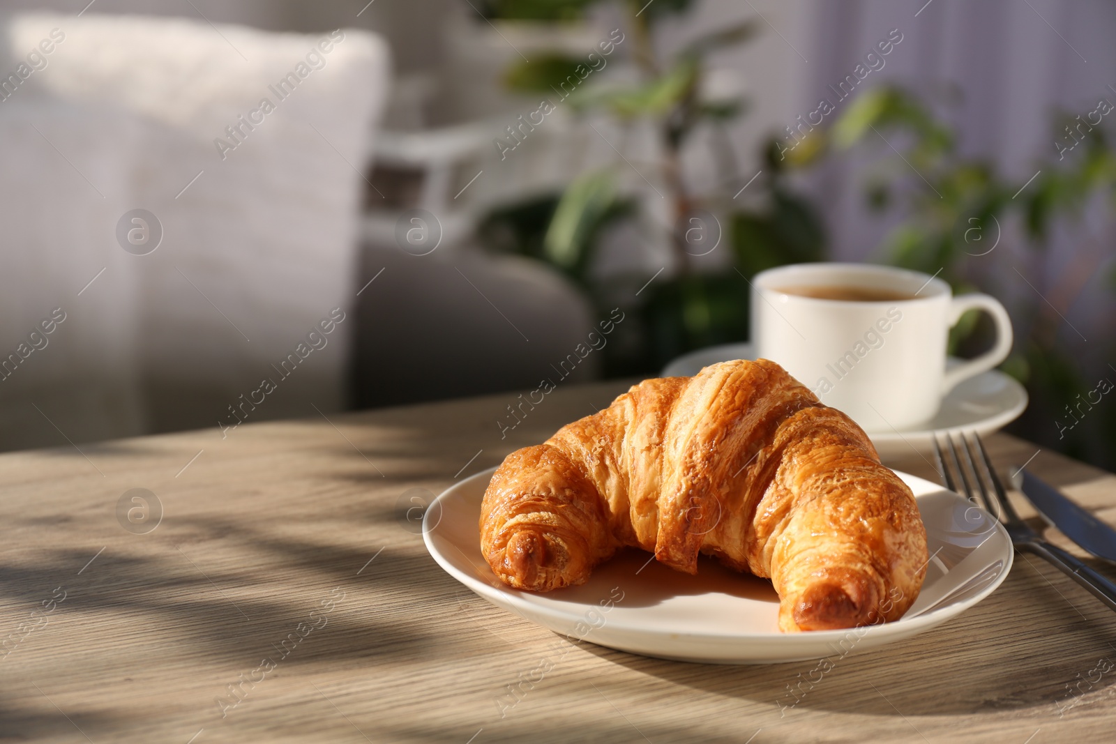 Photo of Delicious fresh croissant served with coffee on wooden table. Space for text