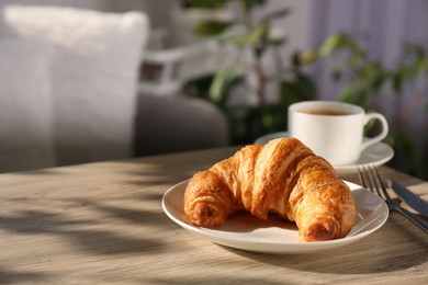 Delicious fresh croissant served with coffee on wooden table. Space for text