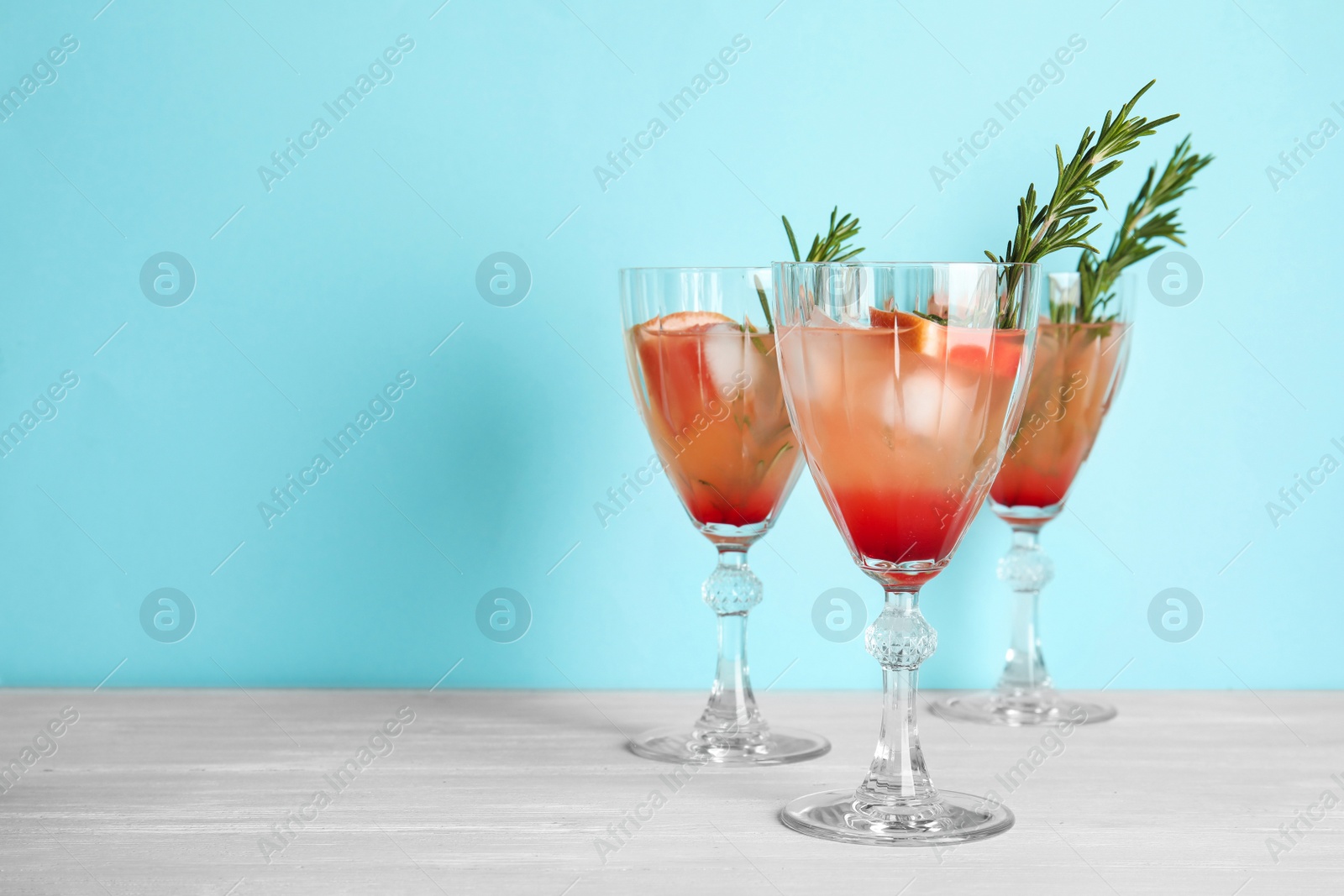 Photo of Glasses of grapefruit cocktails on table against color background. Space for text