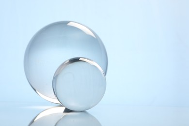 Photo of Transparent glass balls on mirror surface against light background. Space for text