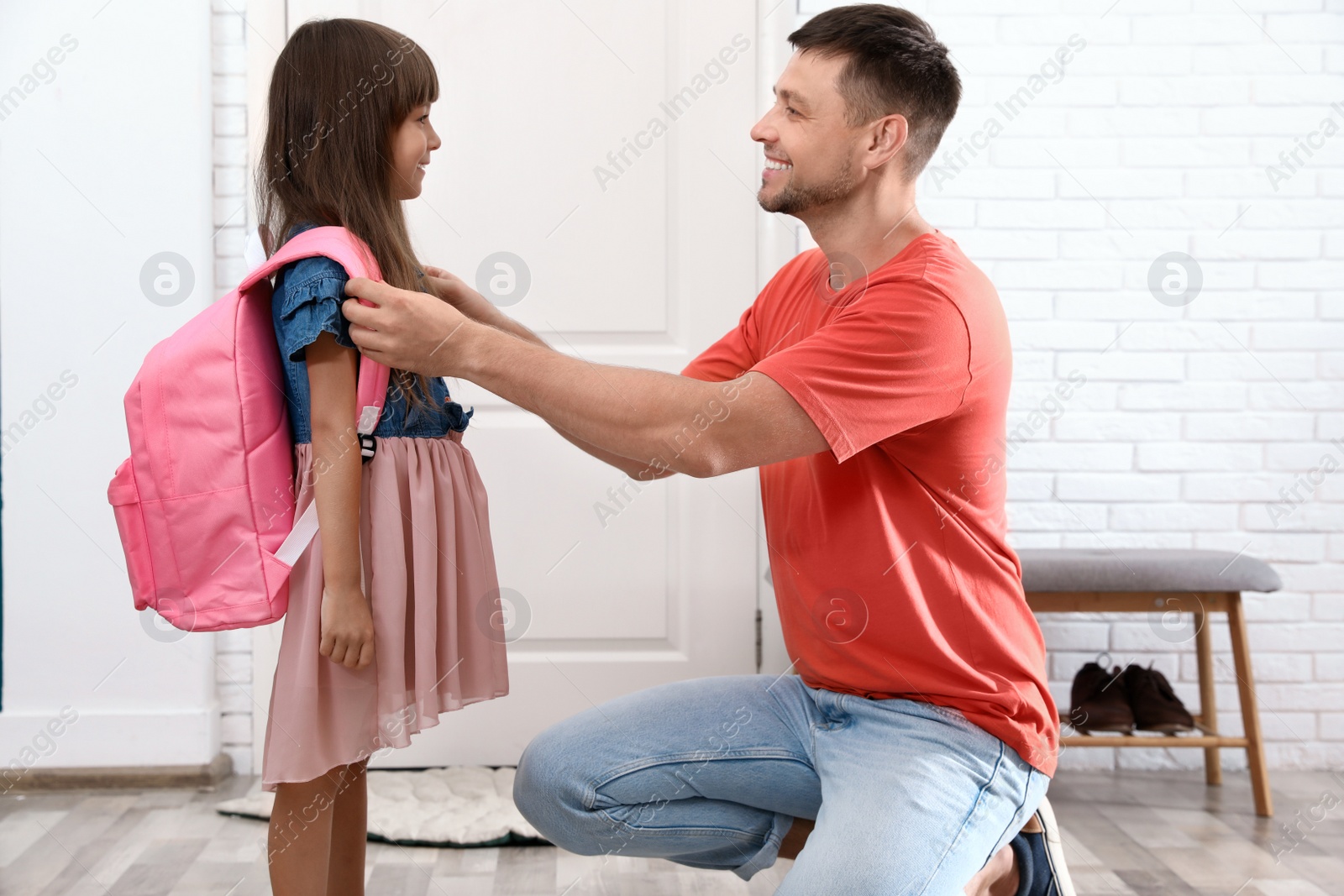 Photo of Happy father helping his little child to put on school bag at home