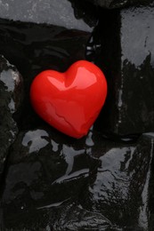 Photo of Red decorative heart on stones and water, top view