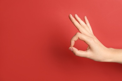 Photo of Woman showing okay gesture on color background, space for text