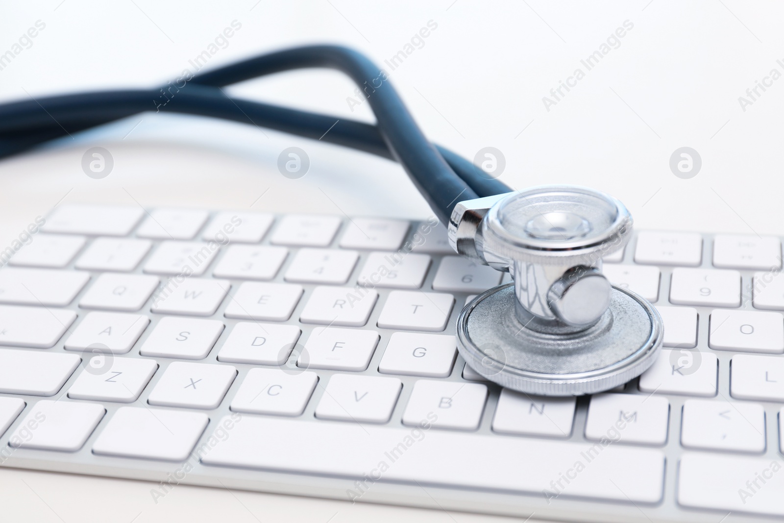 Photo of Modern keyboard and stethoscope on light background. Technical support concept