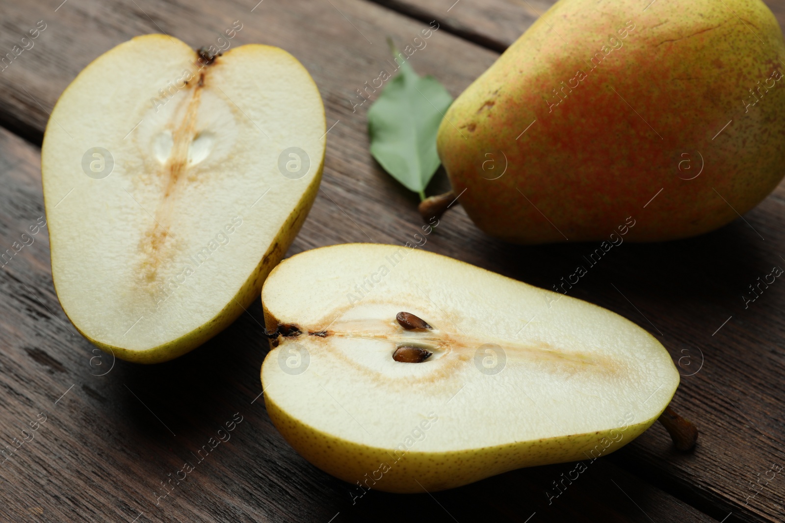 Photo of Whole and half of tasty fresh pears on wooden table, closeup