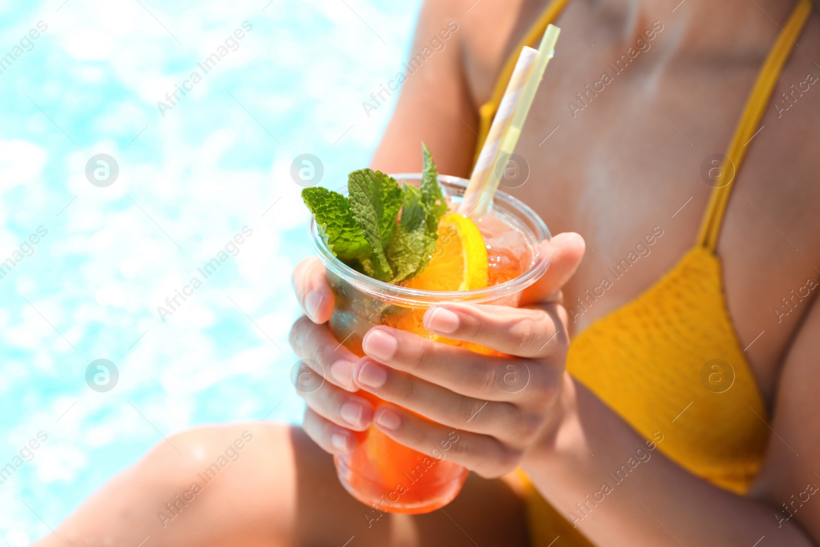 Photo of Woman with glass of refreshing drink near swimming pool, closeup