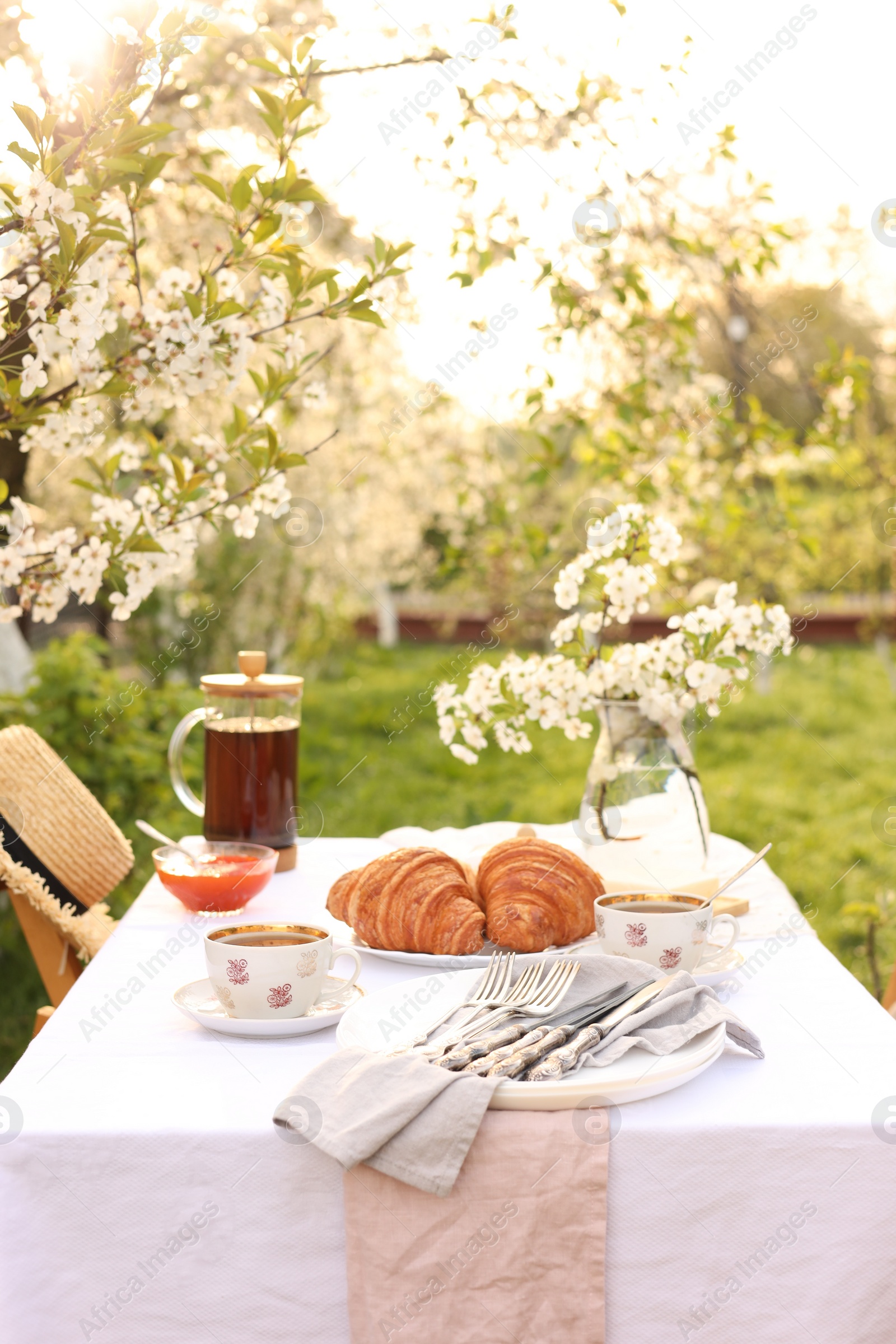 Photo of Stylish table setting with tea and croissants in spring garden