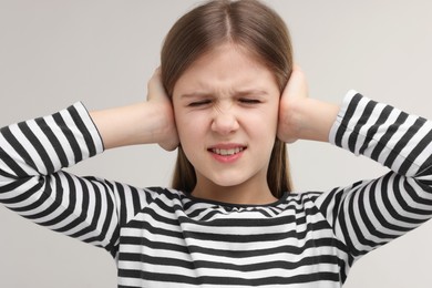 Photo of Hearing problem. Little girl suffering from ear pain on grey background