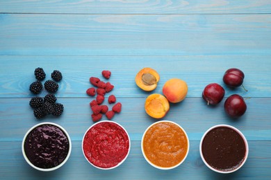 Photo of Different puree in bowls and fresh fruits on light blue wooden table, flat lay. Space for text