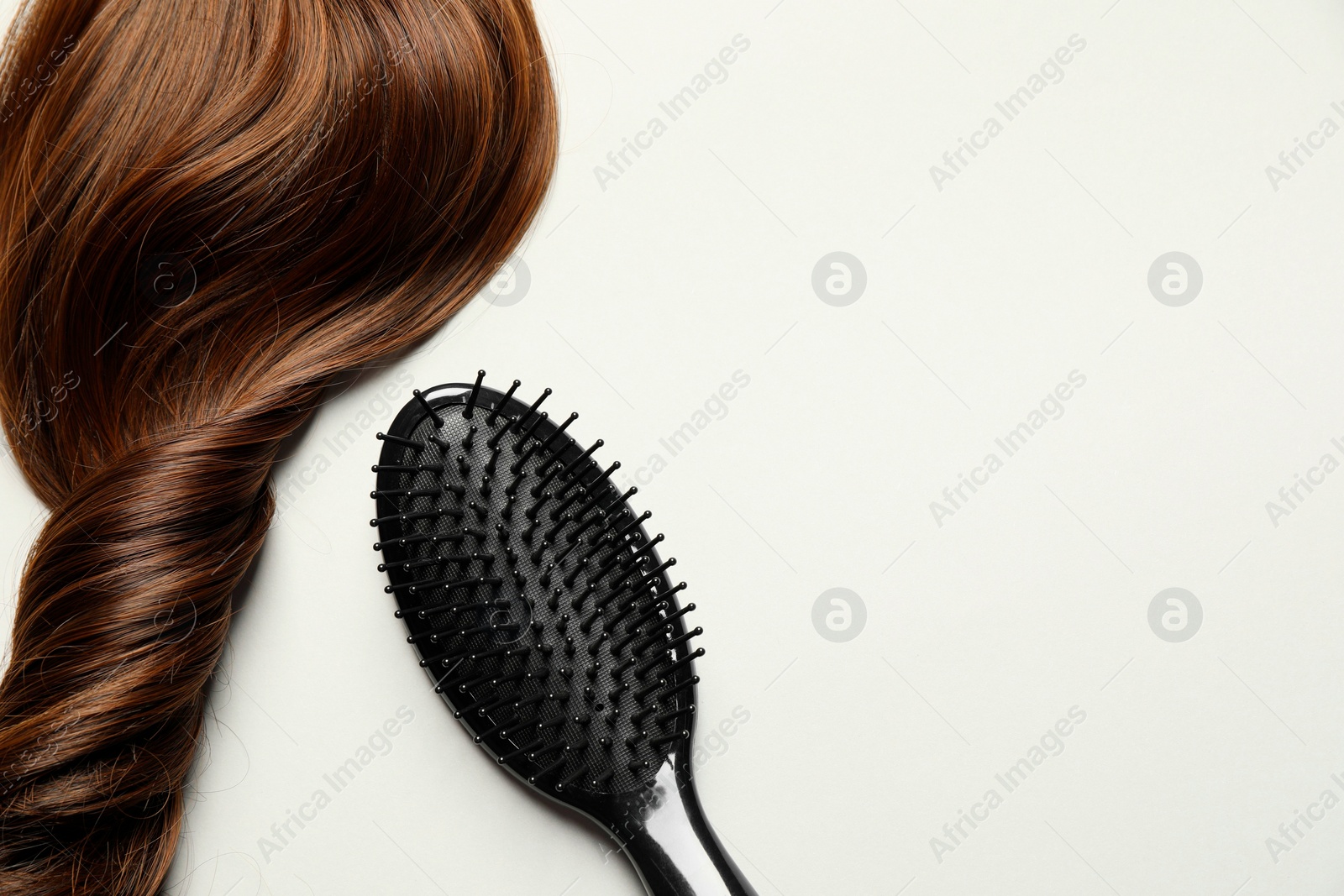 Photo of Stylish brush with brown hair strand on light grey background, top view. Space for text