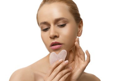 Photo of Beautiful young woman doing facial massage with gua sha tool on white background, closeup