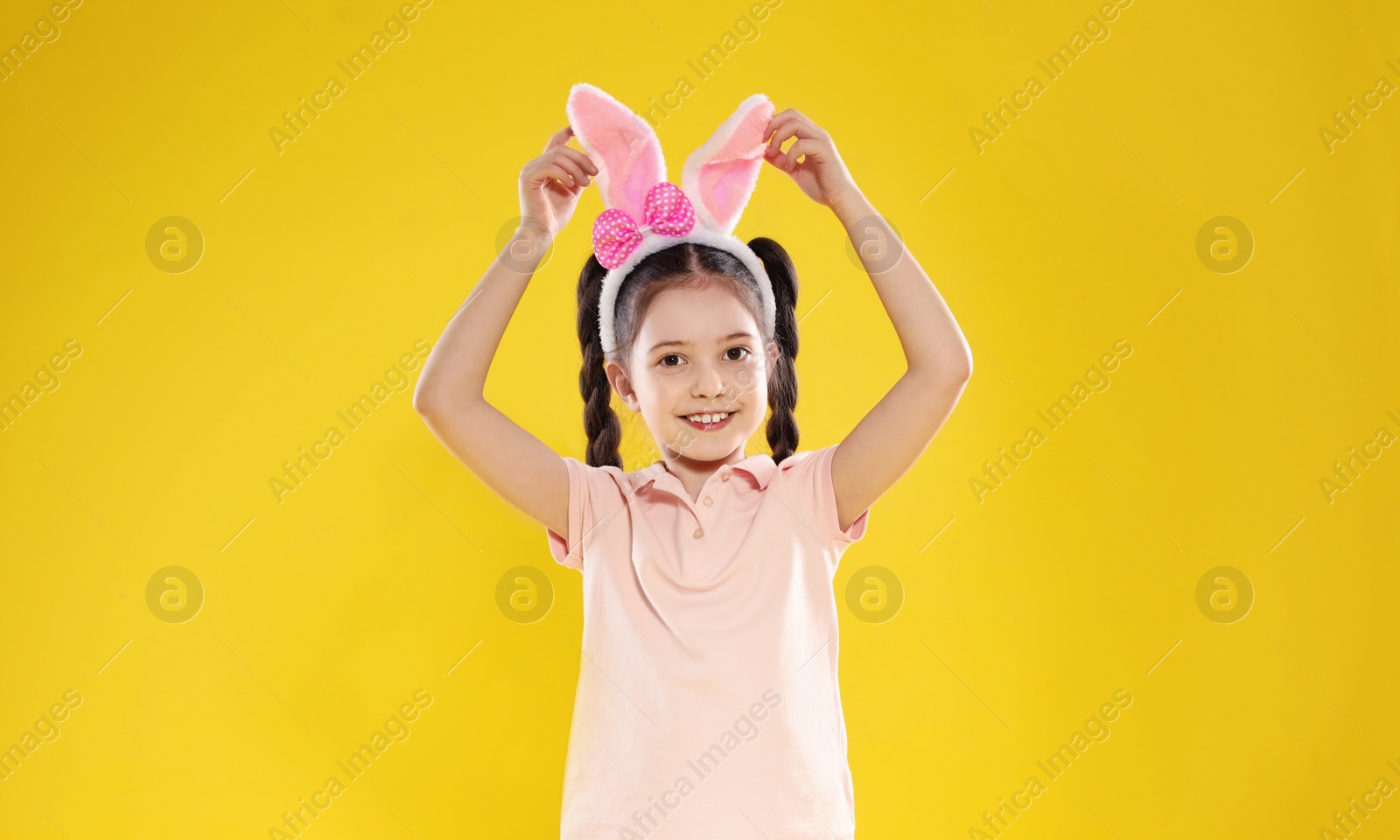 Photo of Portrait of little girl in Easter bunny ears headband on color background