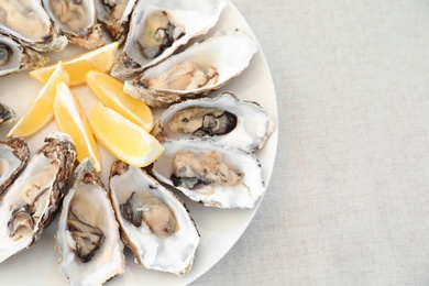 Fresh oysters with cut juicy lemon and space for text on table, top view