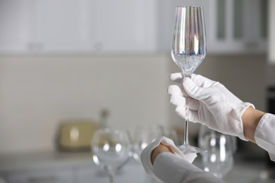 Person in white gloves checking cleanliness of glass indoors, closeup. Space for text