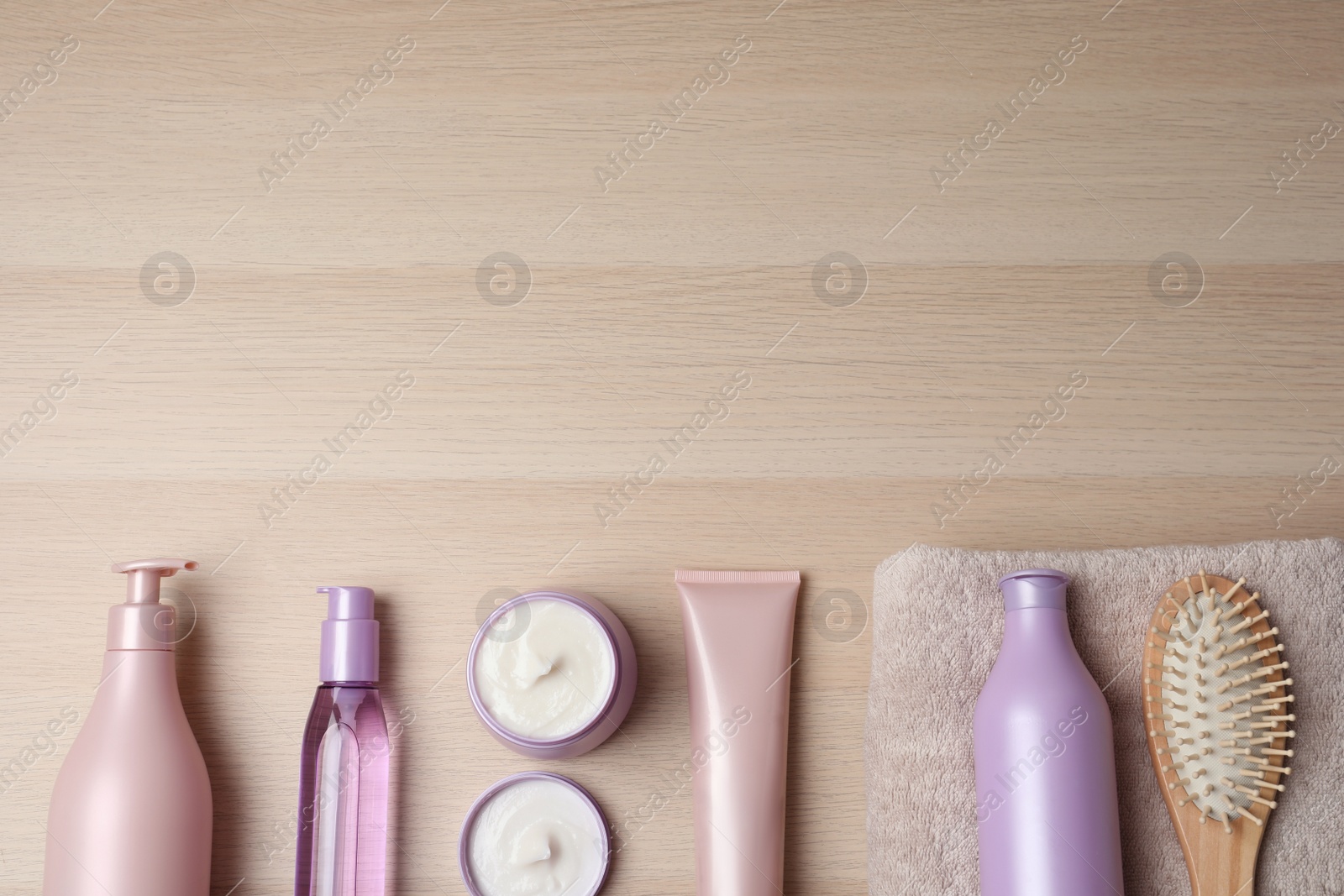Photo of Different hair care products, towel and brush on wooden table, flat lay. Space for text