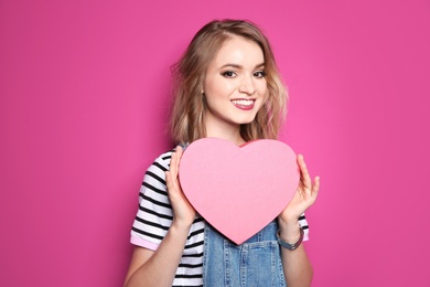 Photo of Beautiful young woman with pink heart posing on color background