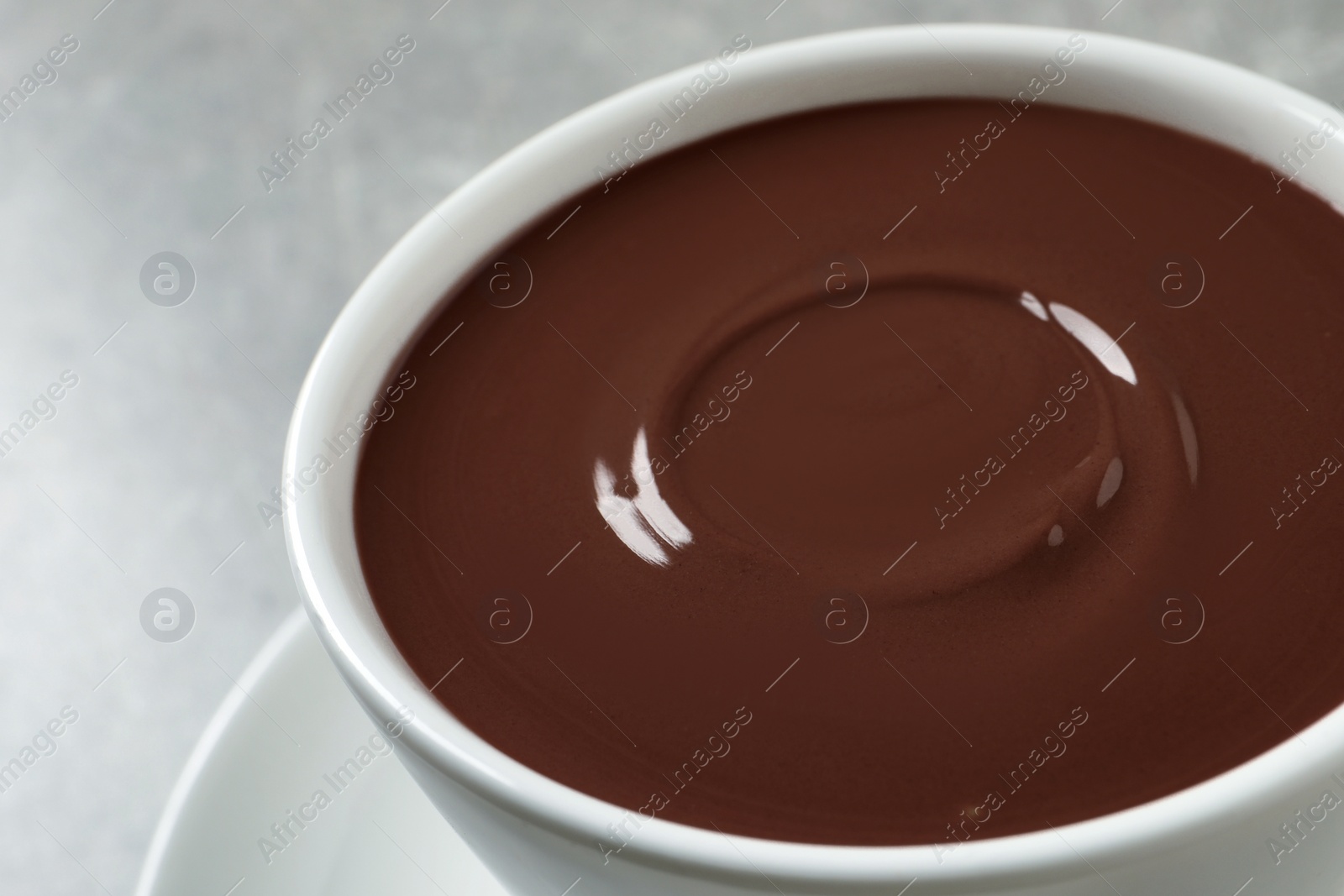 Photo of Yummy hot chocolate in cup on light grey background, closeup