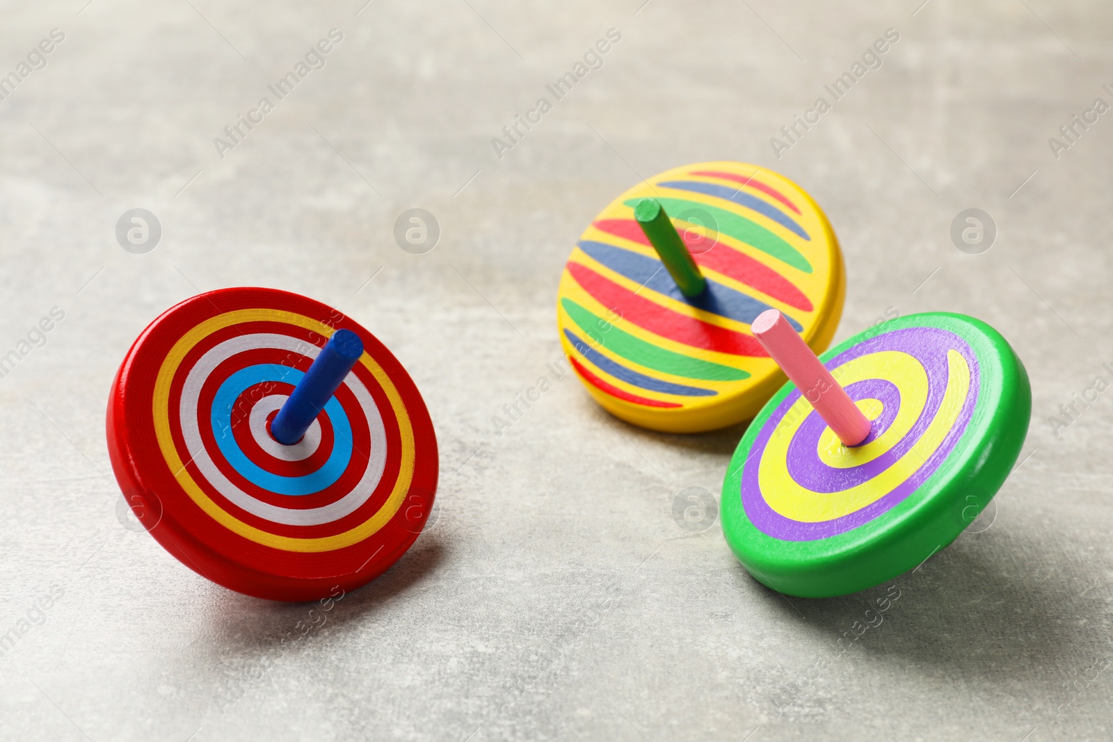 Photo of Bright spinning tops on grey textured background, closeup