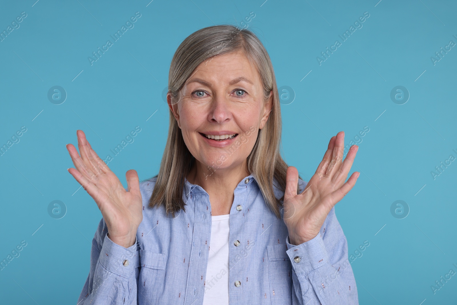 Photo of Portrait of happy surprised senior woman on light blue background
