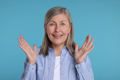 Photo of Portrait of happy surprised senior woman on light blue background