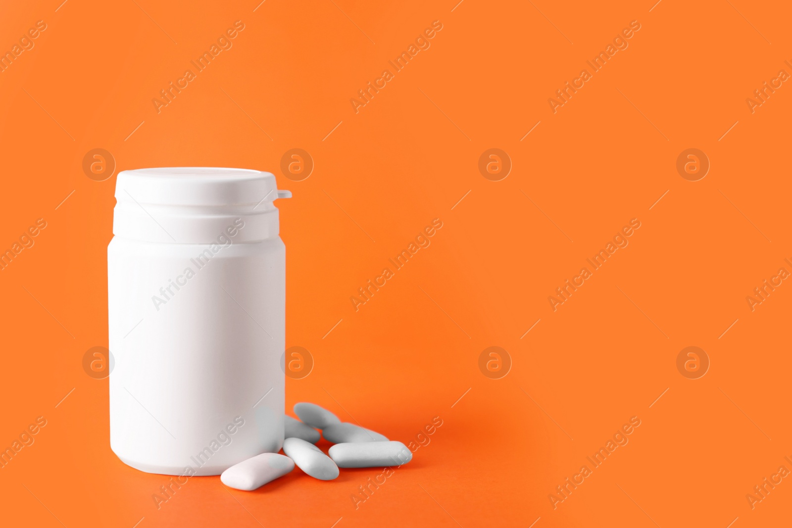 Photo of Jar with chewing gums on orange background. Space for text