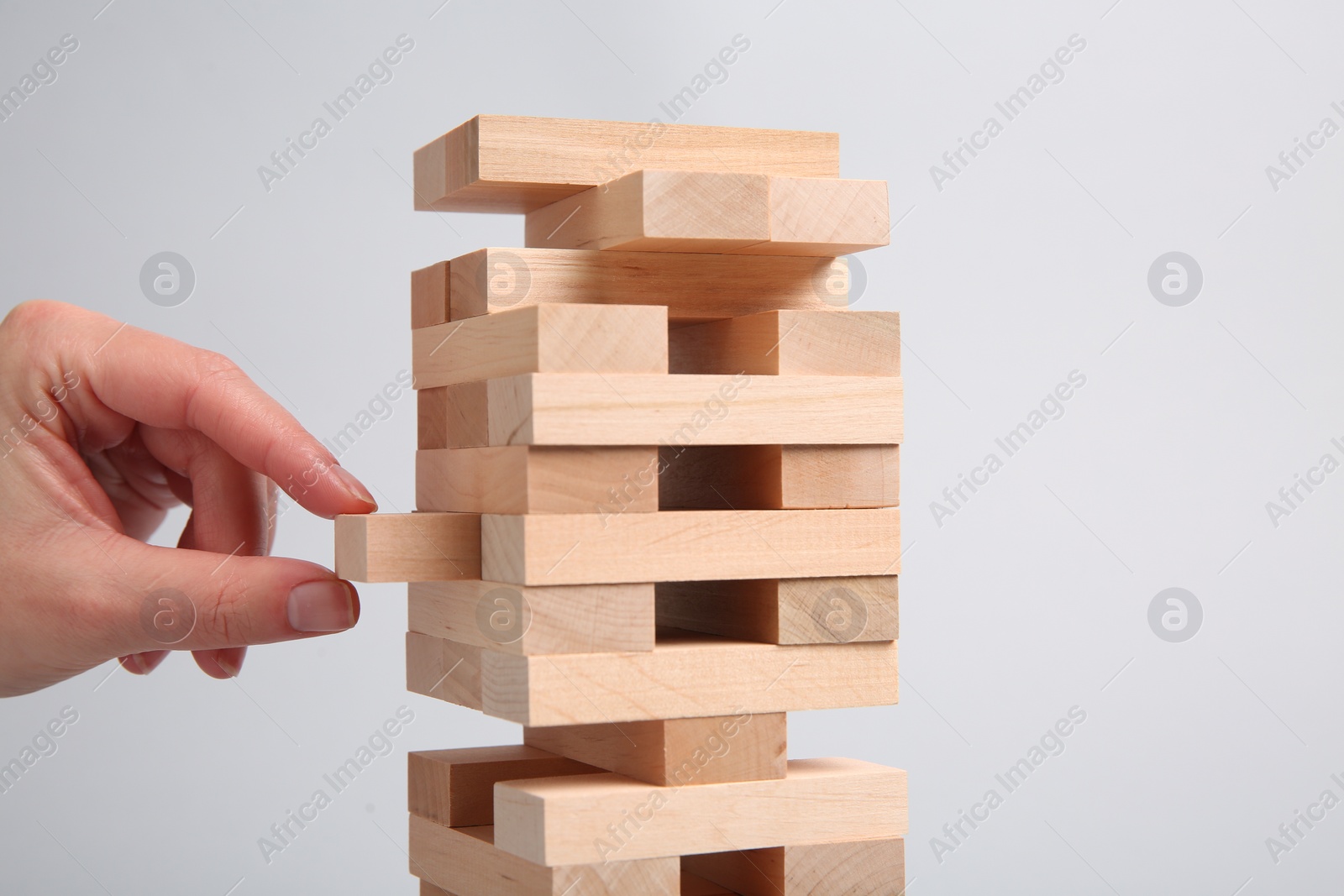 Photo of Woman playing Jenga on light gray background, closeup