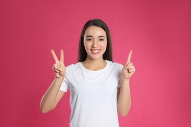 Photo of Woman showing number three with her hands on pink background