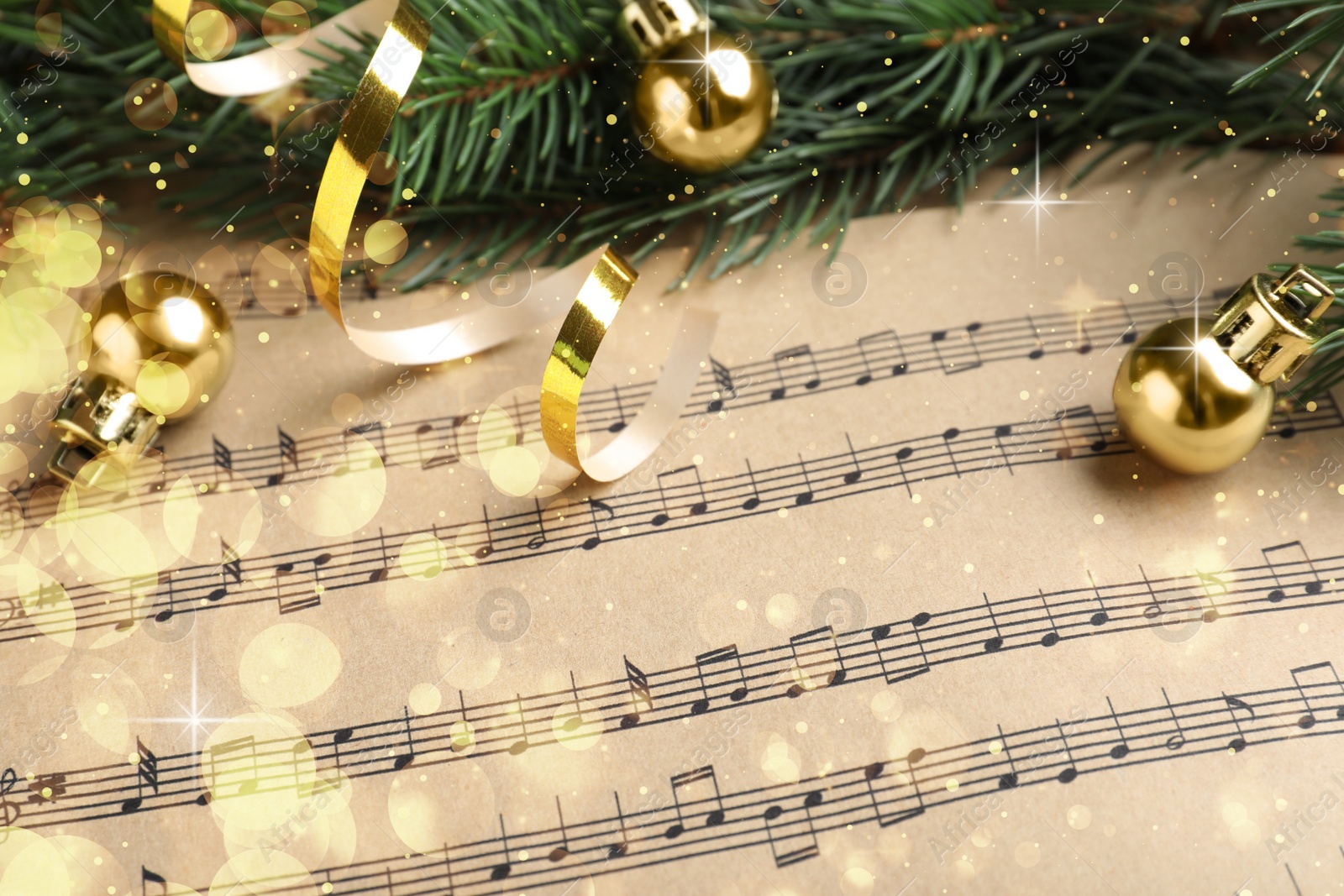 Image of Fir branches and golden balls on Christmas music sheets, above view. Bokeh effect