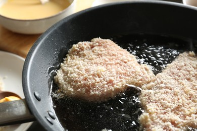 Photo of Cooking schnitzels in frying pan, closeup view