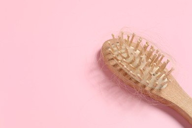 Photo of Wooden brush with lost hair on pink background, space for text