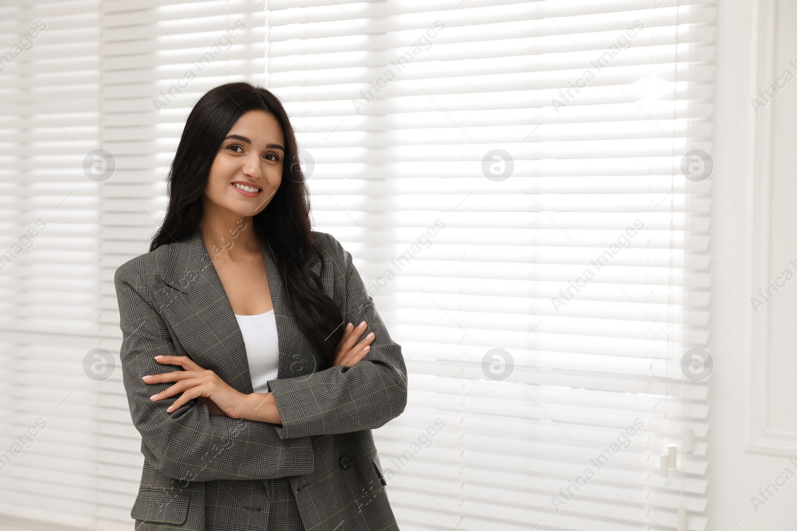 Photo of Beautiful woman in formal suit near window, space for text. Business attire