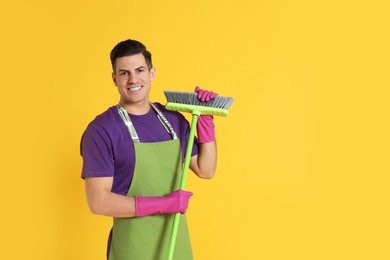 Photo of Man with green broom on orange background, space for text