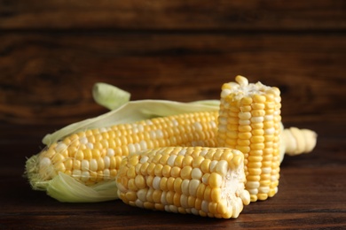 Photo of Tasty sweet corn cobs on wooden table, closeup