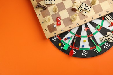 Photo of Different types of board games and its' components on orange background, flat lay. Space for text