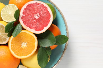 Different cut and whole citrus fruits on white wooden table, top view. Space for text