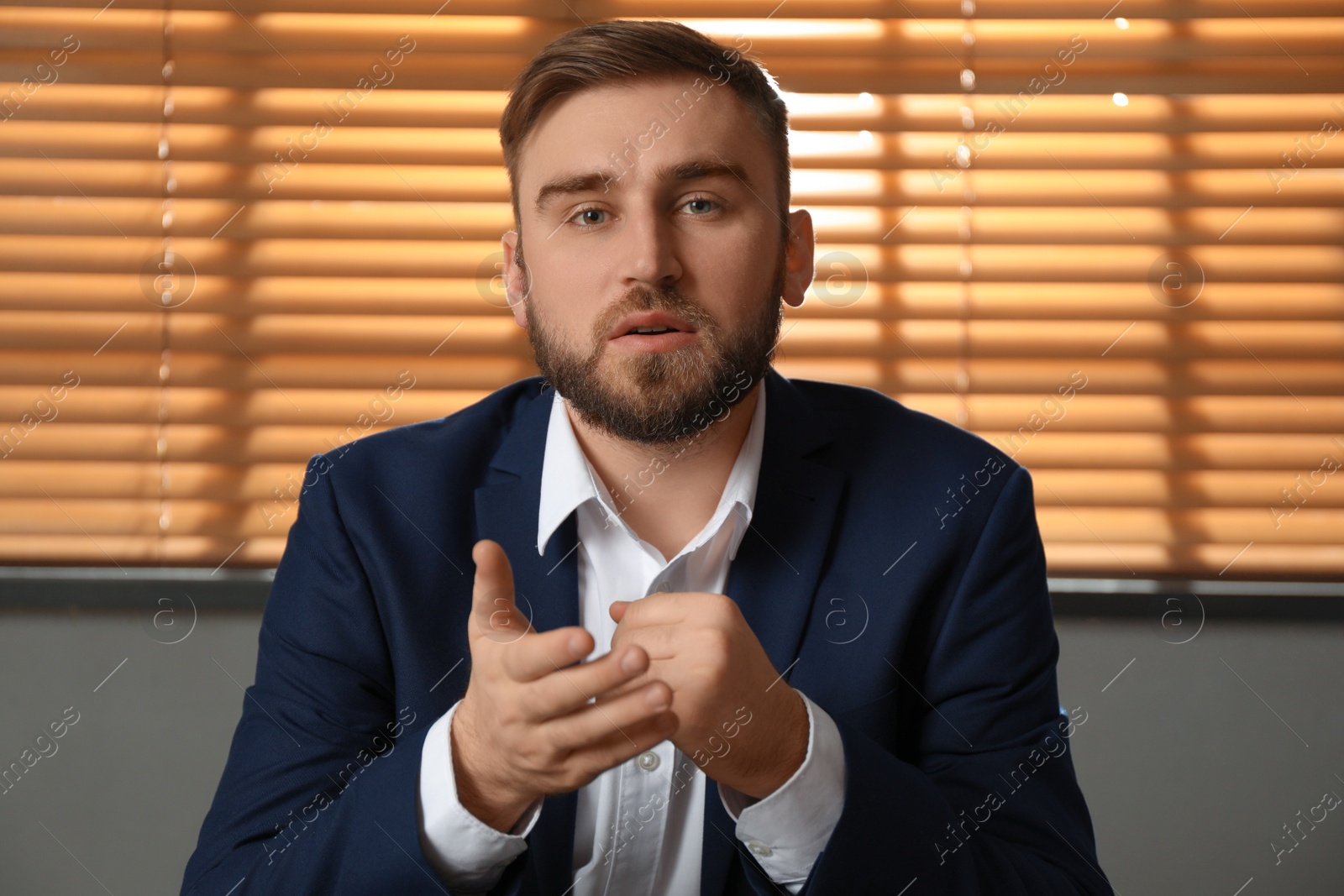 Photo of Young man in suit holding online webinar indoors, view from webcam