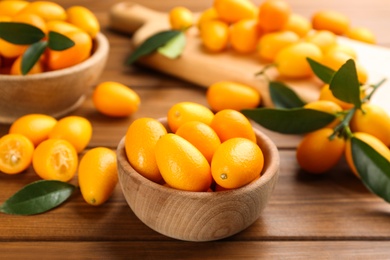 Fresh ripe kumquats with green leaves on wooden table
